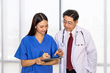 Happy Asian male and female medical doctor standing and discussing about case with notepad