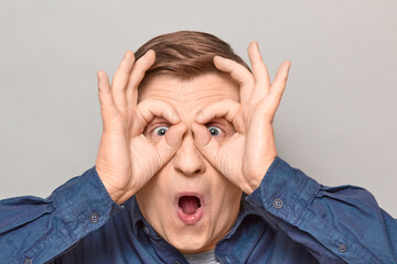 Portrait of amazed man making binoculars with hands and looking afar