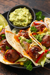 Meat free beetroot and pea protein meatballs taco wraps with avocado guacamole, sweet chilli sauce and lime wedges