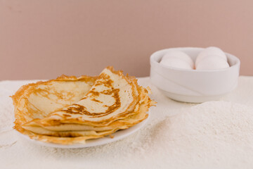 beautiful round thin pancakes on the kitchen table with flour and whisk and eggs