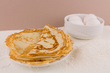 beautiful round thin pancakes on the kitchen table with flour and whisk and eggs
