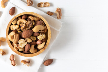 Top view of mixed nuts in a wooden bowl on white background