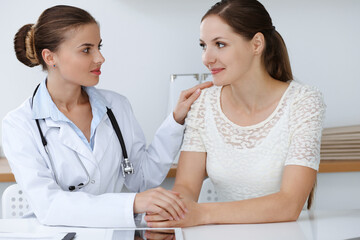 Woman-doctor reassuring her female patient while sitting at the desk. Medicine concept