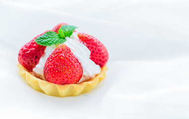 Strawberry Tart with mint leaf on cream cheese on white cloth