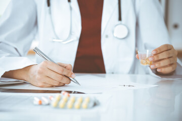 Unknown woman-doctor fills up prescription form. close-up. Panacea and life save, prescribe treatment, legal drug store. Medicine concept