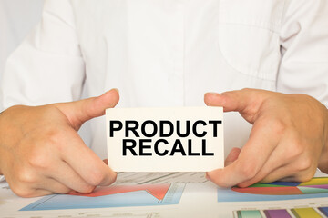 a man in the office holds a card with text PRODUCT RECALL . business concept