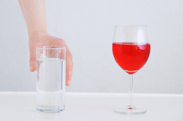 Alcohol refusal concept. Glass of water and wine.  He takes a glass of water with his hand.