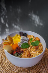 Eating healthy breakfast bowl. Mango smoothie bowl with granola, seeds , almond fresh apple in White ceramic bowl.detox, vegetarian, vegan food concept 
