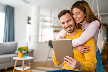 Happy cheerful couple in love using digital tablet at home