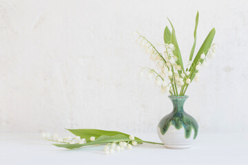 lily of the valley in little vase on background old white wall