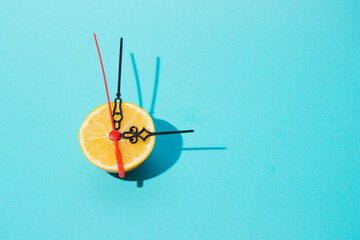 Creative and trend  idea with clock hands-on lemon with turquoise  Background. Minimal composition.