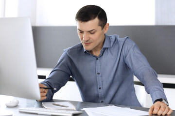Businessman working with computer in modern office. Headshot of male entrepreneur or company...