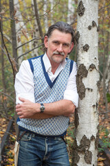 Naklejka na ściany i meble portrait of handsome man in his 50s standing in the forest