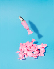 A creative idea of a fish jumping out of the isolation of a pink candy on a cyan background....