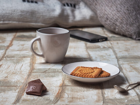 Light breakfast with cookies and chake in white ceramic dishes and pieces of chocolate
