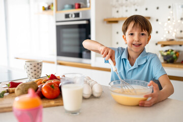 Happy child prepare food and having fun in kitchen. Healthy eating.