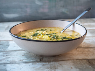Lunch with soup with dumplings and dill in a light ceramic plate on a light table
