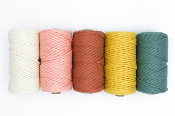 Close-up view of the colorful single strand cotton cords for macrame DIY handcraft on white...