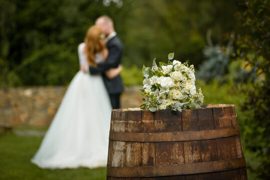 Wedding bouquet on a barrel against the background of the bride and groom at a ceremony in blur
