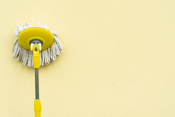 Yellow mop with bright yellow cement wall,minimal style,blank space with text