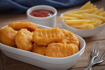 Crispy chicken nuggets and french fries in bowl.