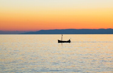 Fishing boat at sunset around the bay of Kardamyli village in Messiniaki Mani region of south Peloponnese in Greece.