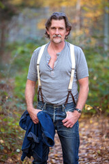 portrait of handsome man in his 50s standing in the forest