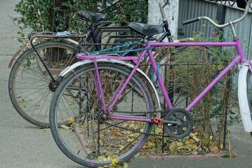 Fototapeta na wymiar two old bicycles stand on a rural street on gray asphalt