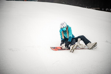 Stylish sporty woman is getting her snowboard binding ready