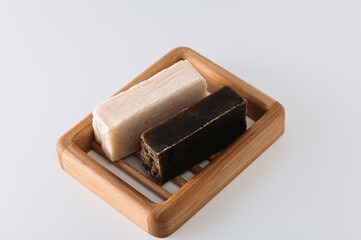 natural handmade olive and tar soap on a wooden soap dish, side view, light background