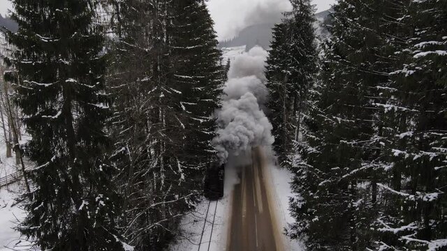 Old train Mocanita with big smoke during winter time in Moldovita, Bucovina. Romania. Filmed from above with drone.