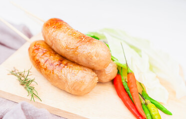 Thai style sausage, made from glass noodles, lean pork with garlic, pepper, coriander seed, seasoning sauce, grilled. placed on a plate with fresh cauliflower and chili. Thai street food