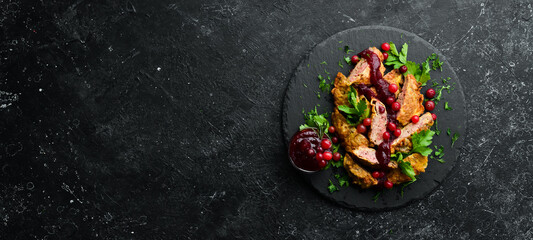 Fried chicken liver with cranberry sauce and cranberries on a black stone plate. Rustic style. Top view.