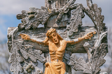 Ancient gilded stone sculpture of Jesus Christ, crucified on a cross.