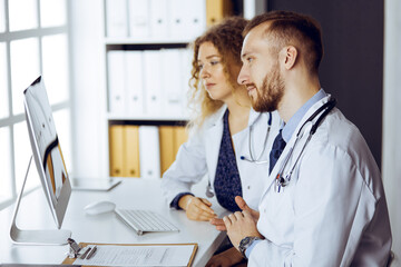 Red-bearded doctor with female colleague discussing current disease therapy while sitting at...