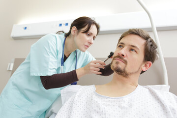 physician looking into male patient ear with an instrument