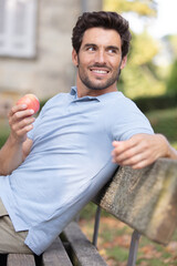 fit man eating an apple in the countryside