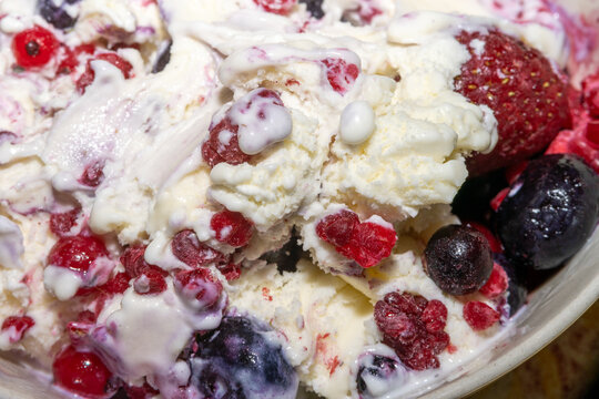 A closeup picture of vanilla ice cream with blue berries, red currants and raspberries