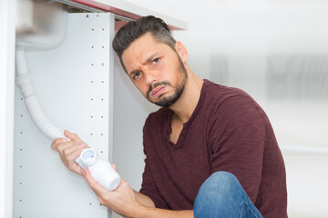 man making a facial expression while holding a plumbing tube