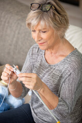 cheerful elderly woman holding knitting needles