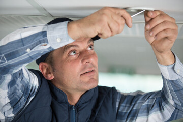 builder drives screws into ceiling