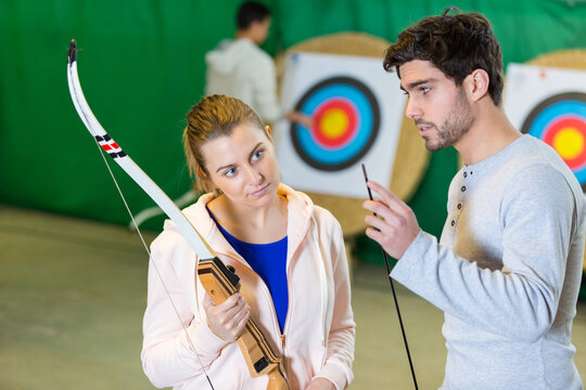 young man and woman inspecting archery arrow - Powered by Adobe