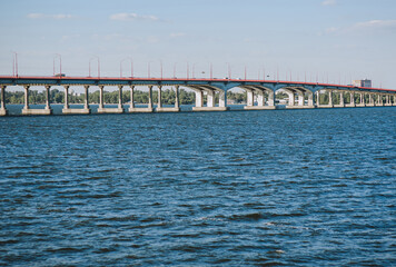 A large, high biton bridge stands on the blue Dnieper River. 