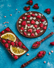 Diet dark chocolate without sugar based on cocoa and stevia with the addition of freeze-dried berries, nuts and fruits. Top view on blue background