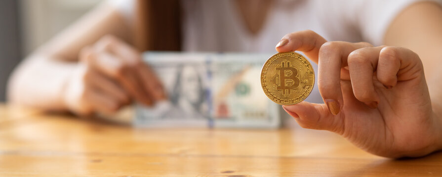 Woman hand holding bitcoin and dollars