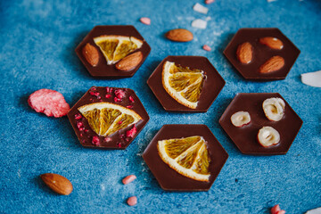 Diet dark chocolate without sugar based on cocoa and stevia with the addition of freeze-dried berries, nuts and fruits. Top view on blue background