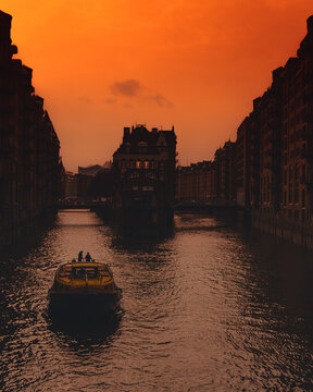 White boat on river between buildings during sunset