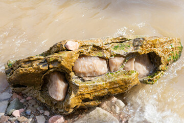 Large gypsum rock or stone surrounded by water. Big wet calcite washed in the river shore with lots of waves. Semi Precious white gem deposit or mining
