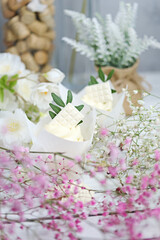 Several cupcakes and muffins with white butter cream on a white wooden table. Valentine's day or Mother's Day gift. Fresh flowers are on the table nearby. Rustic style.