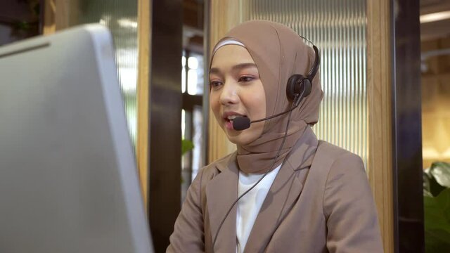Beautiful Asian Muslim women wearing hijab working in call center office, Confident Islam woman worker in Customer Support smiling joyful to Support Customers
